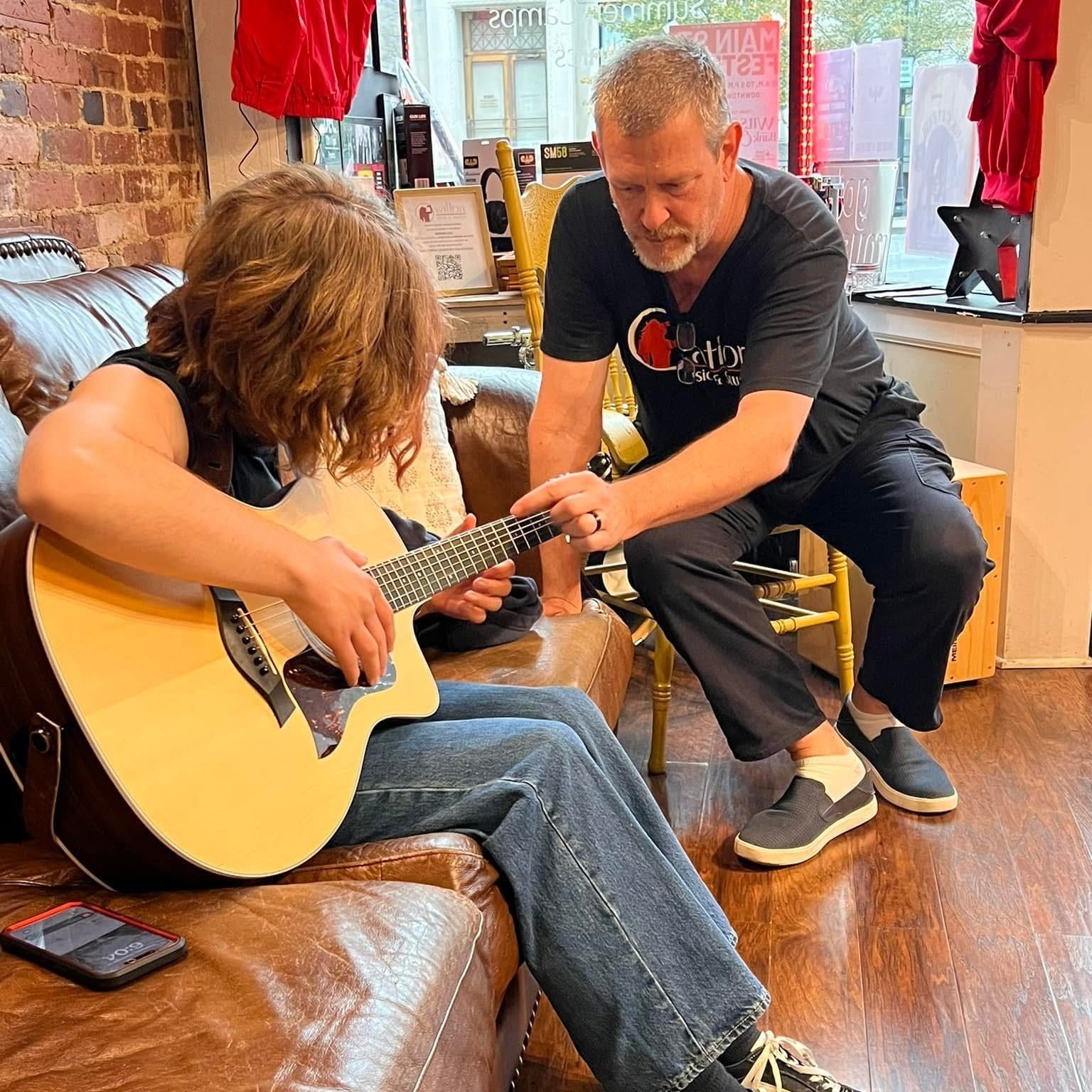 An Ovation instructor teaching a student guitar during a private lesson.