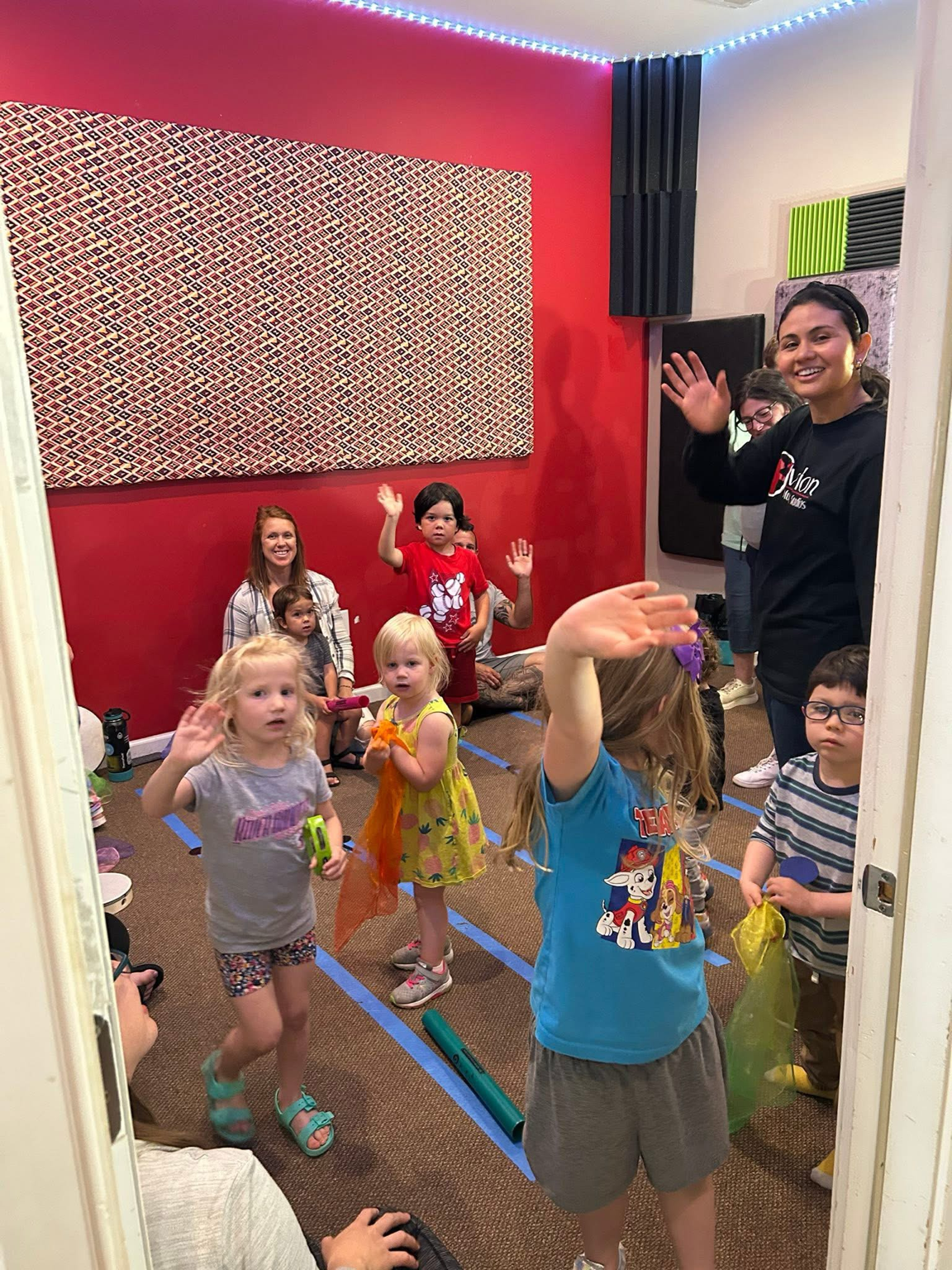 Young children waving and dancing with their teacher in an Ovation Little Rockers class.
