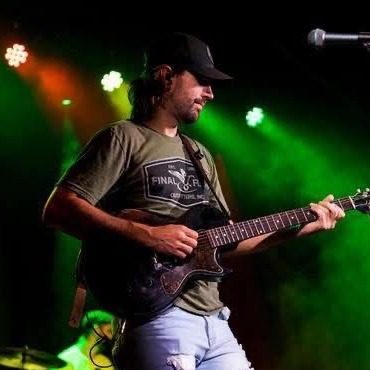 Portrait of Ovation instructor Brandon Blackburn playing electric guitar on stage.