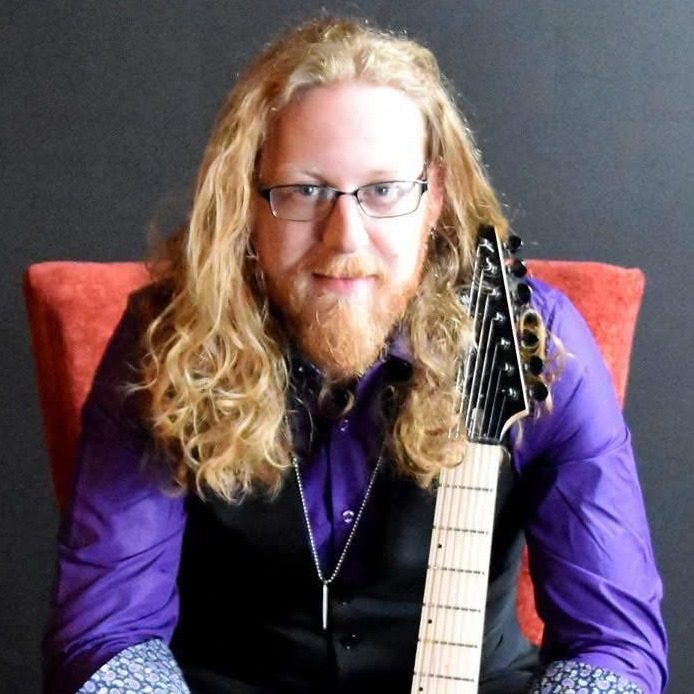 Portrait of Ovation instructor Randy Scott Peterson holding an electric guitar.