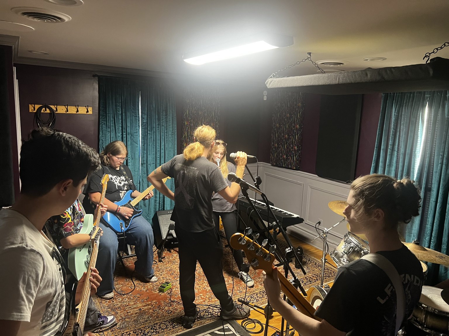 Students playing guitars and bass together at an Ovation Student Open Jam.